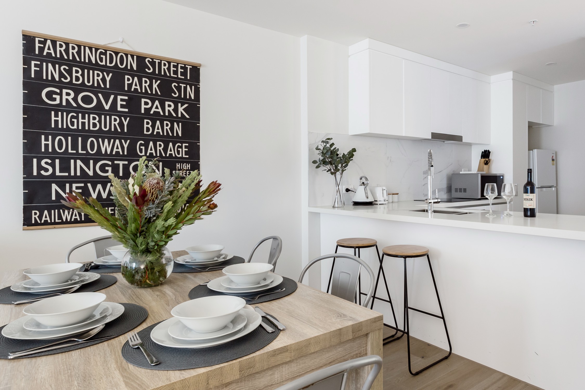 Set dining table, guest wine displayed on breakfast bar. | custombnb